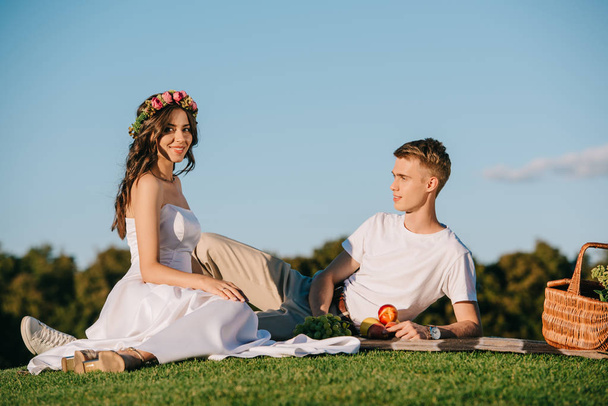beautiful wedding couple resting on picnic with fruits - Fotografie, Obrázek