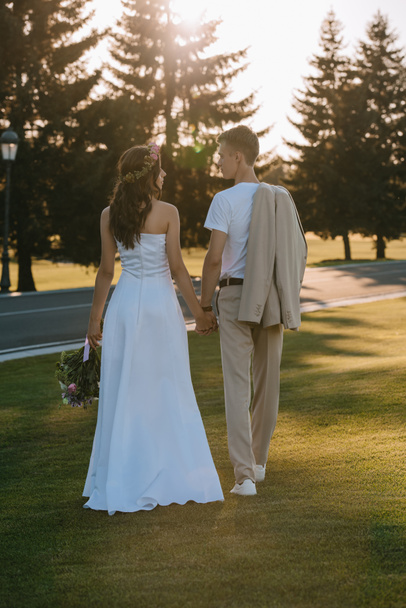 back view of beautiful bride and groom holding hands   - Fotografie, Obrázek