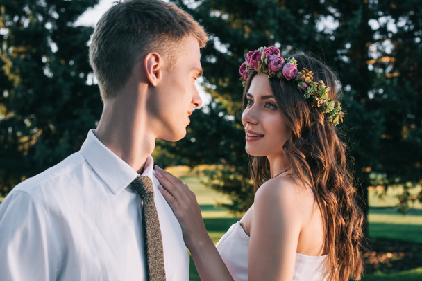 beautiful romantic young wedding couple smiling each other in park - Fotó, kép