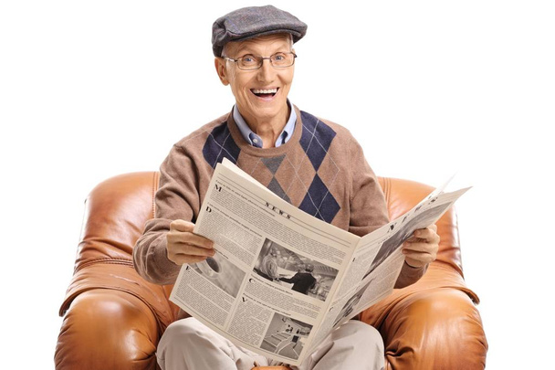 Elderly man with a newspaper sitting in a leather armchair isolated on white background - Photo, Image
