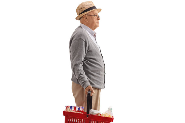 Profile shot of a senior with a shopping basket isolated on white background - Foto, Imagen