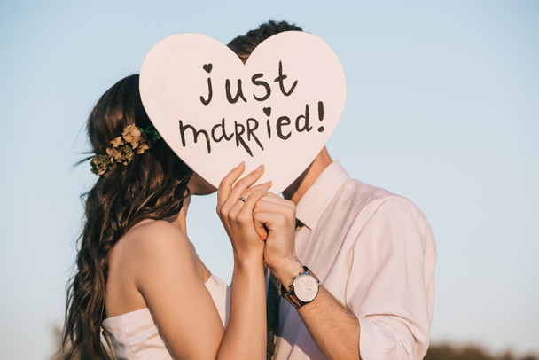 young wedding couple kissing and holding heart with just married inscription  - Photo, Image