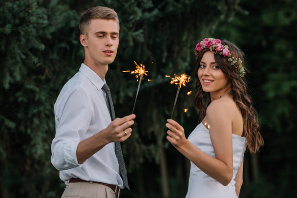 szczęśliwy ślub Młoda para trzymając ognie i uśmiecha się do kamery - Zdjęcie, obraz