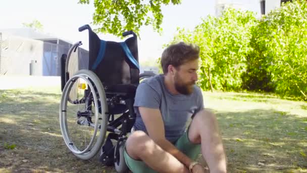 junger behinderter Mann versucht, sich im Rollstuhl hinzusetzen - Filmmaterial, Video