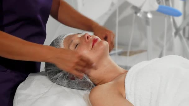 Happy senior woman getting face and neck massage at spa - Footage, Video