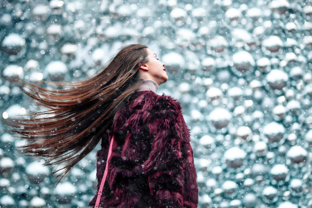 Outdoor close up portrait of young beautiful girl with long hair young girl Dynamically walking down the street. Hair trembles in the wind.Snowfall - Фото, изображение