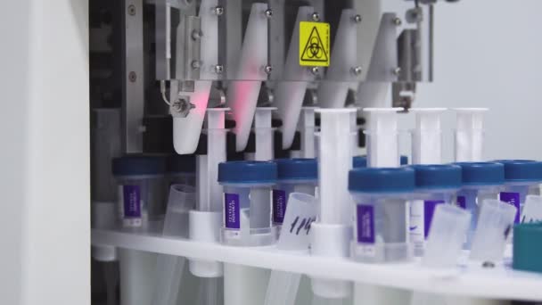 Close-up in het medisch laboratorium, de robot doorboort een pot van vloeistof met een naald en giet het in een buis voor verdere analyse door de arts - Video