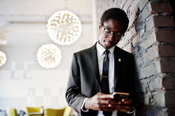 Business african american man wear on black suit and glasses at office looking on mobile phone. - Foto, Imagem