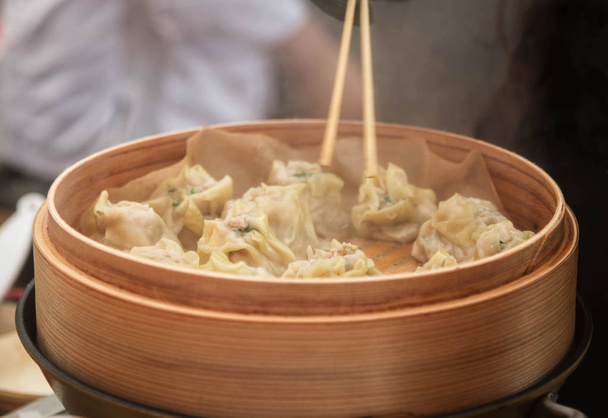 Steamed Korean Mandu dumplings with chicken and vegetables in a bamboo steamer. In a street restaurant - Photo, Image