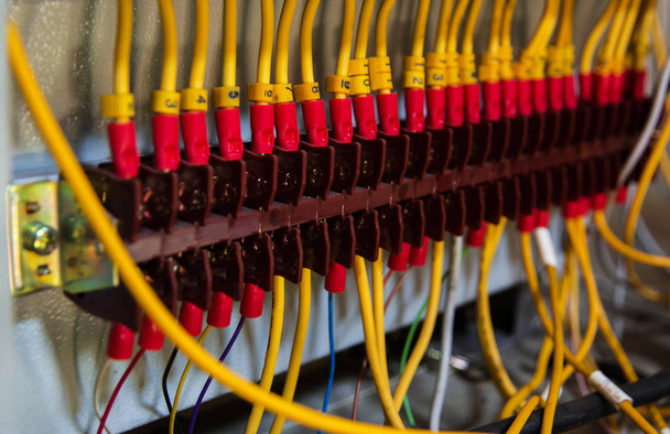 O fio elétrico na caixa de tensão, o painel de controle instrial com fios, o sistema elétrico, luz embaçada ao redor
. - Foto, Imagem