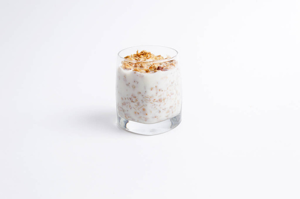 Glass full of muesli and milk on a white background  - Foto, afbeelding