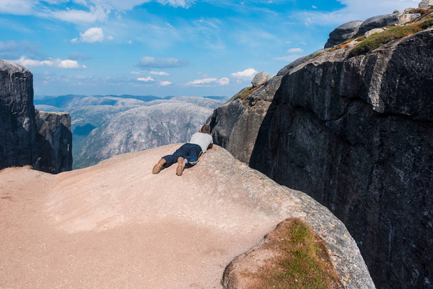 Porträt einer extremen Planreise für den gutaussehenden alten Mann auf dem Stein des kjerag in den Bergen kjeragbolten Norwegens, Selfie mit dem Smartphone in der Hand - Foto, Bild