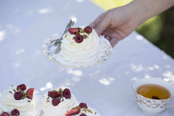 woman  holding pavlova cake. Pavlova cakes with cream and fresh summer berries - Fotoğraf, Görsel