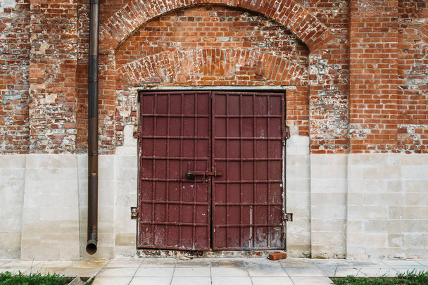 Steel gates or door in red brick wall with grass at ancient church - 写真・画像