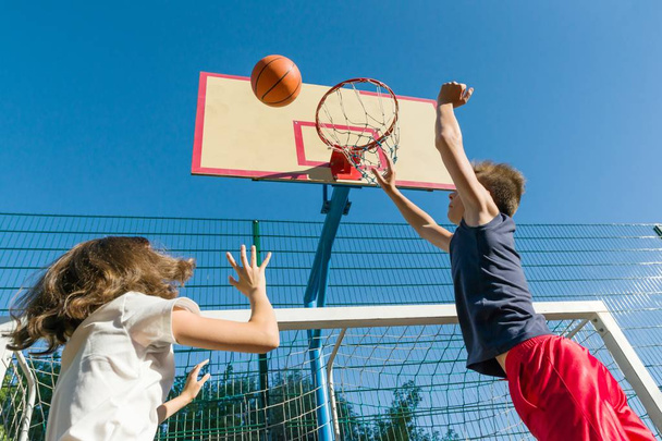 Streetball basketball game with two players, teenagers girl and boy, morning on basketball court - Photo, image