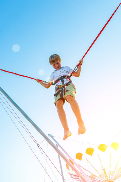 Smilling excited boy jumping on a trampoline with insurance. - Φωτογραφία, εικόνα