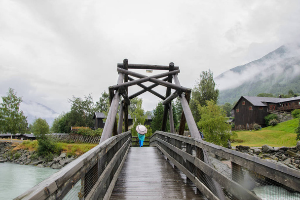 Rapariga debaixo de um guarda-chuva numa ponte, Noruega. Menina sob um guarda-chuva em uma ponte de madeira, Norway.Image de uma menina sob um guarda-chuva que está andando em uma ponte de madeira velha durante uma chuva, Noruega
. - Foto, Imagem