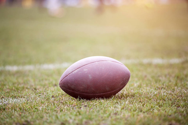 Close up of an american football on the field, players in the background - Photo, Image