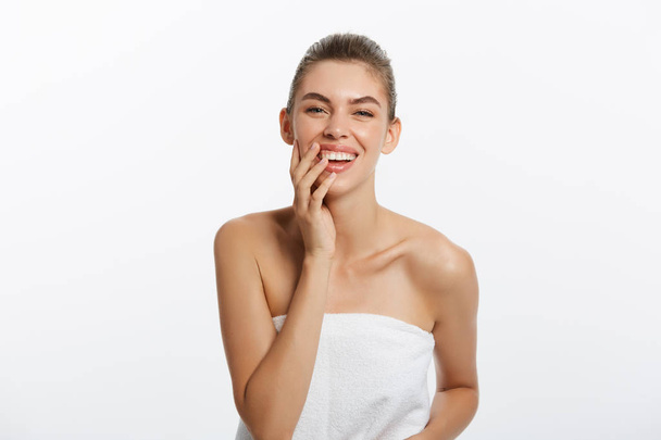 Kaunis hymyilevä tyttö puhtaalla iholla, luonnollinen meikki, ja valkoiset hampaat harmaalla taustalla
 - Valokuva, kuva