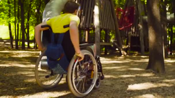 Mladá zakázat muž na invalidním vozíku v parku - Záběry, video