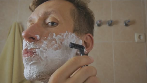 Close-up of caucasian man shaving in front of mirror. - Filmati, video