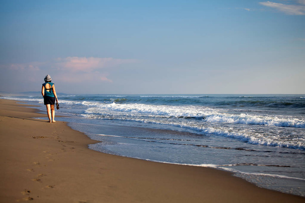 Young woman walking along the beach - Fotoğraf, Görsel