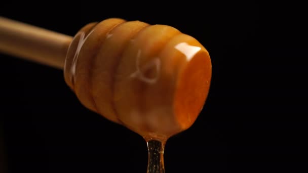 Biologische honing beeldmateriaal druipend uit houten honing lepel achtergrond - Video