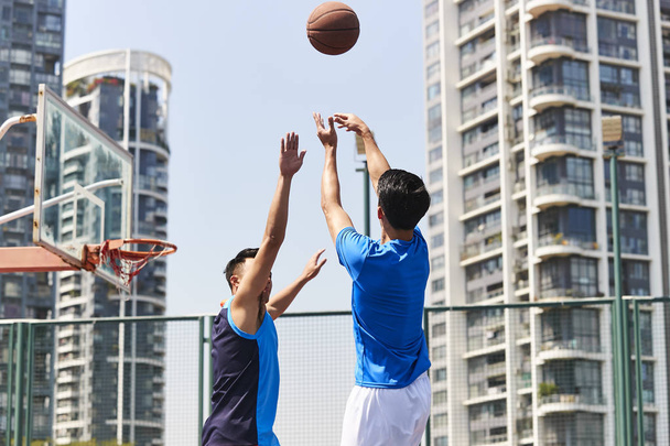 молодые азиатские взрослые игроки играют в баскетбол на открытой площадке
. - Фото, изображение