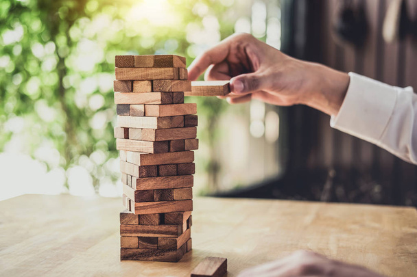 Images of hand of businesspeople placing and pulling wood block on the tower, Alternative risk concept, plan and strategy in business, Risk To Make Business Growth Concept With Wooden Blocks. - Fotografie, Obrázek