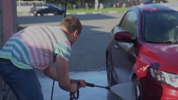 Young caucasian man washing his car on the car wash self-service. Car washing. - Video
