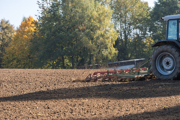 Lavori dell'agricoltore con trattore ed erpice sul terreno - dettaglio
 - Foto, immagini