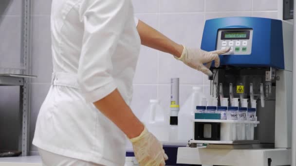 Dziewczyna ustawia próbki damskie ginekologiczne płynu do analizy na raka, zautomatyzowanych badań - Materiał filmowy, wideo