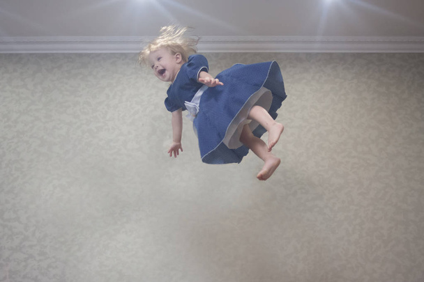 dive into the air. little girl is lightening under the ceiling - Фото, изображение