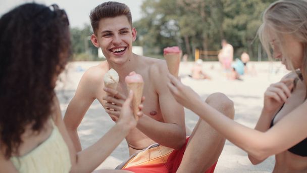 Three friends having fun, outdoors. Young people enjoying a day on the beach and eating ice creams. - Foto, Imagen