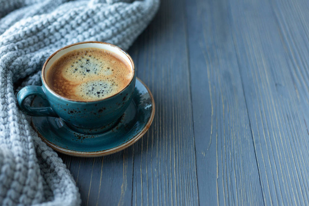 Blue cup whith coffee, knitted sweater, autumn leaves on wooden background. Cozy morning. - Foto, Bild