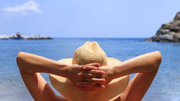 Viajes, vocación, concepto de vacaciones. Mujer en sombrero está tumbado en la tumbona en la playa por mar
. - Foto, Imagen
