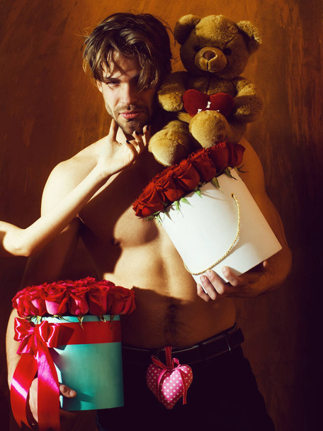 bearded muscular man with sexy body holds red rose box - Φωτογραφία, εικόνα