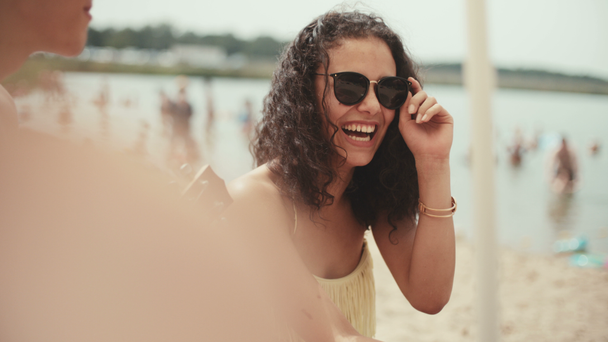 Arkadaş grubu sahilde oturan ve gülümseyen Bikini genç kadın portresi. - Video, Çekim