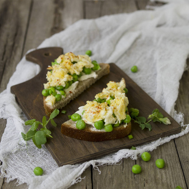 Bruschetta with green peas, cheese and egg. Healthy breakfast. Close up, copy space - 写真・画像