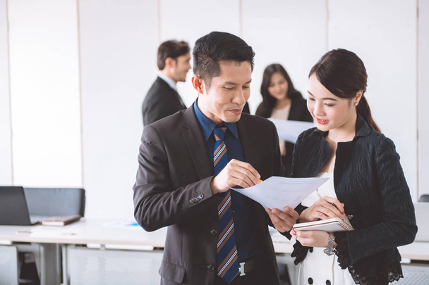 Business team meeting together to brainstrom. Young asian male in suit with beautiful young asia women standing together looking at sale chart. Young generation business team concept. - Foto, Imagem