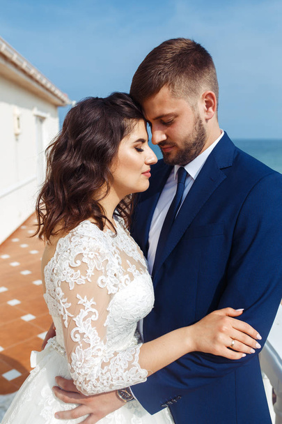 Beautiful Bride and Groom enjoy each other on the background of the ocean. happy romantic young couple celebrating their marriage. Sexy stylish couple of lovers close up portrait. wedding concept. - Photo, image