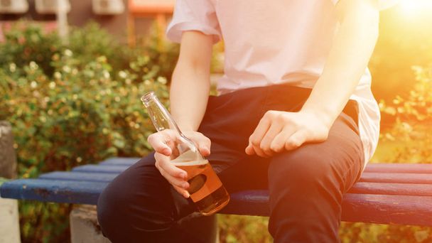 Man sits and holds a bottle of cider. Close view - Photo, Image