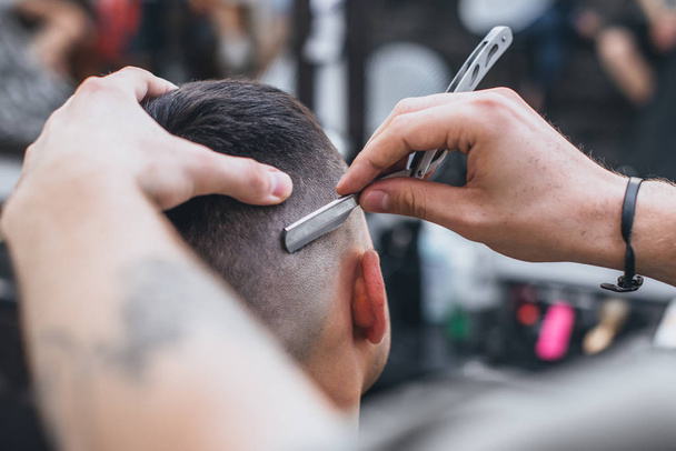 Barber makes an ideal hairstyle. Haircut Fade. Hairdresser performs a dangerous razor . - Fotografie, Obrázek
