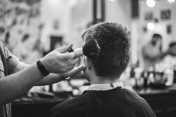 Men's haircut in the beauty salon. Barber makes a haircut to the client. Preparing for a haircut. - Фото, изображение