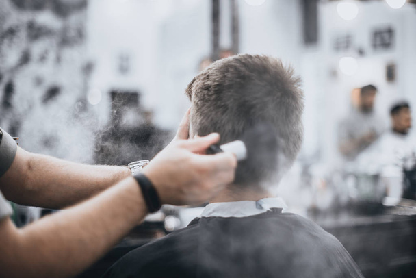 Men's haircut in the beauty salon. Barber makes a haircut to the client. Preparing for a haircut. - Foto, Bild