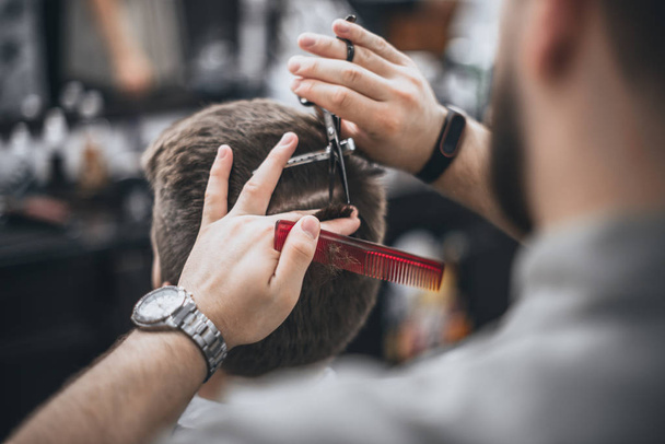 Hair Care. Barber makes a haircut with scissors. Soft focus. - Fotó, kép