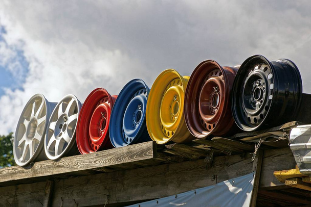 row of old colored discs against the sky and clouds - Photo, Image