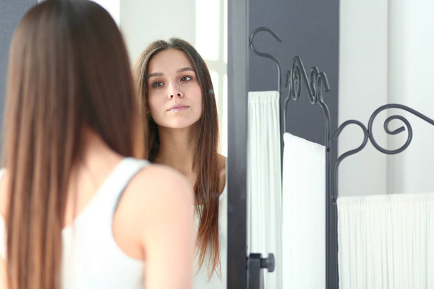 Young woman looking herself reflection in mirror at home. - Φωτογραφία, εικόνα