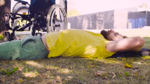 Junger behinderter Mann entspannt sich auf dem Boden im Park - Filmmaterial, Video