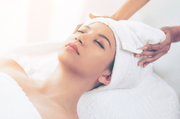 Relaxed young woman lying on spa bed prepared for facial treatment and massage in luxury spa resort. Wellness, stress relief and rejuvenation concept. - Φωτογραφία, εικόνα